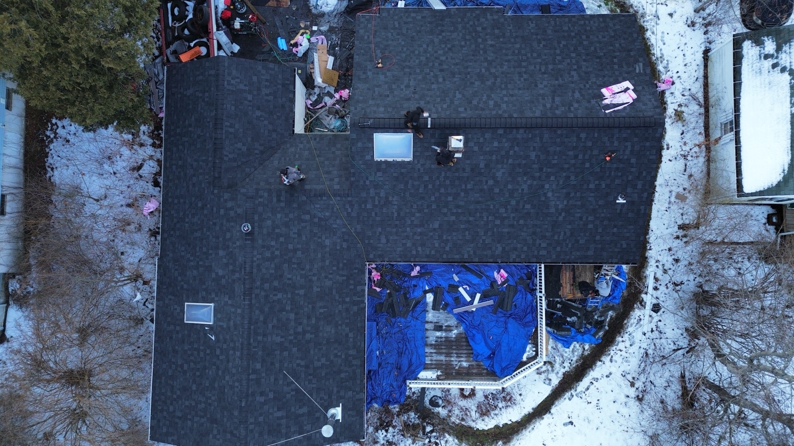 Aerial view of a roof replacement in progress with materials staged on the deck